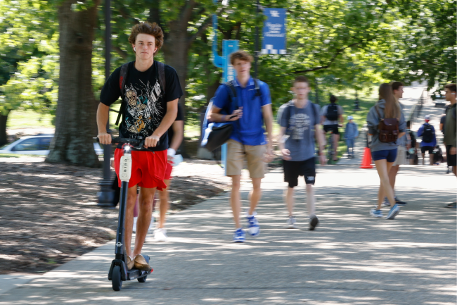 Students going to class. One on a scooter is in focus