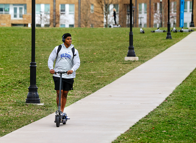 Student riding scooter outside